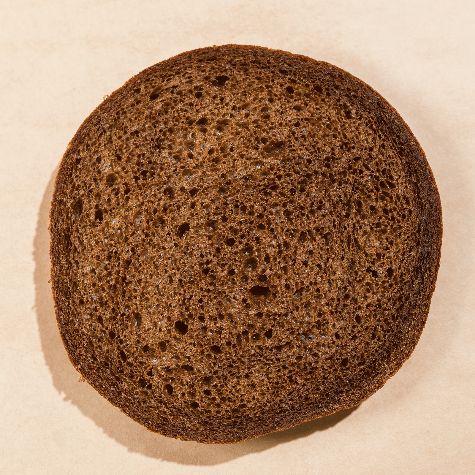 Round cross-section slice of La Segunda pumpernickel bucket bread, dark malty crumb.