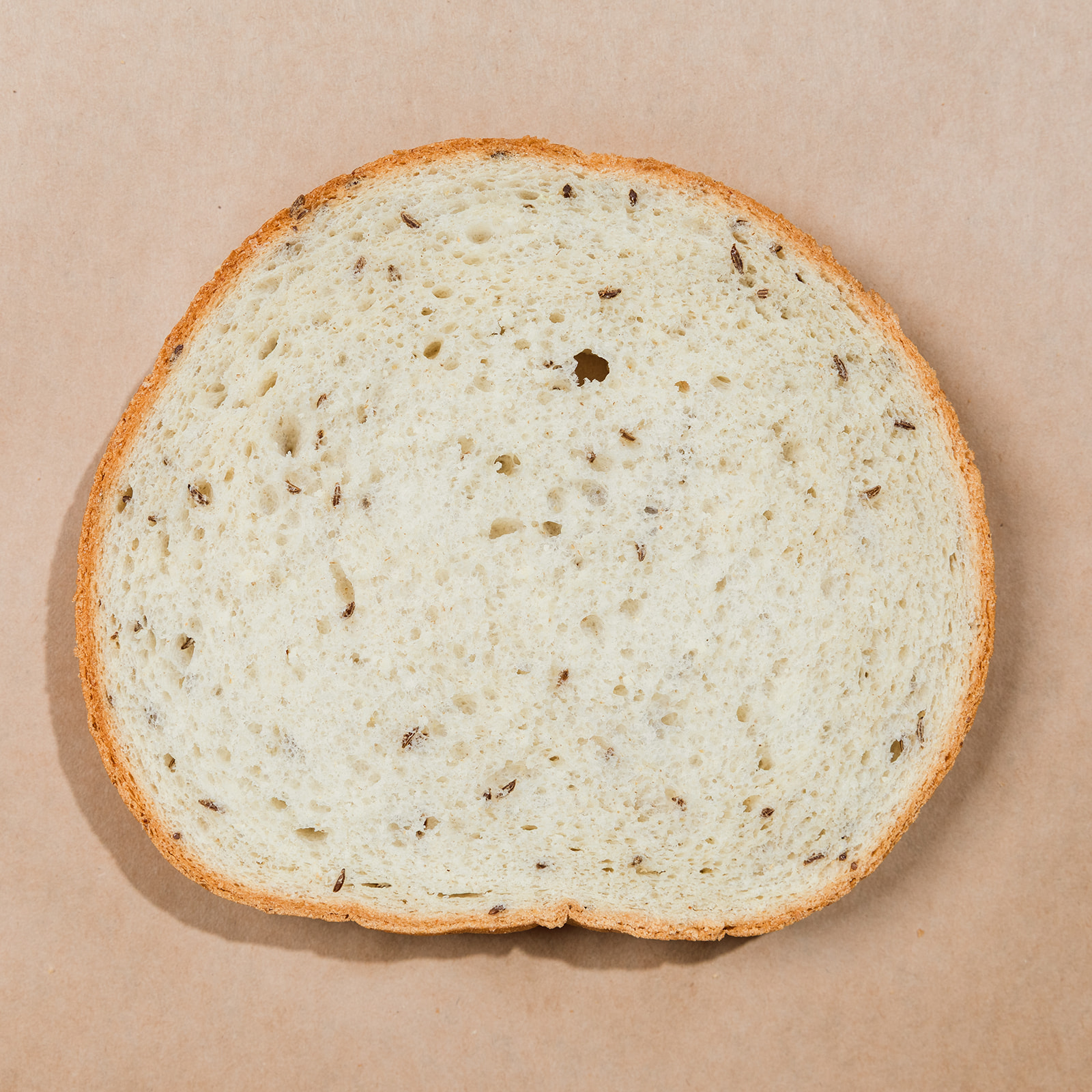 Round cross-section slice of La Segunda rye bucket bread, pale crumb flecked with caraway seeds.